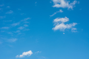 Fototapeta na wymiar Moon on the daylight blue sky with clouds
