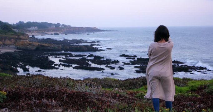 Young female Photographer taking picture of beautiful ocean landscape