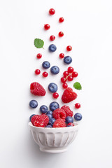 Bowl with heatlhy fresh red fruits (raspberry, blueberry, red currant) isolated on a white background viewed from above. Top view. Flat lay