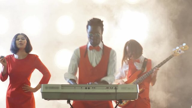 Awesome afro guy playing the musical keyboard between two beautiful women. Music genre. Classical music.