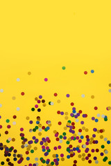 Birthday or party background. Festive greeting card. Yellow background with color confetti