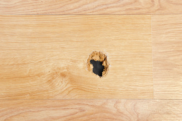 A wooden sheet floor destroyed with a hole at home