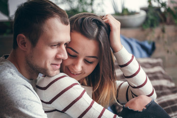 young loving couple sitting on the couch, kissing and hugging, newlyweds