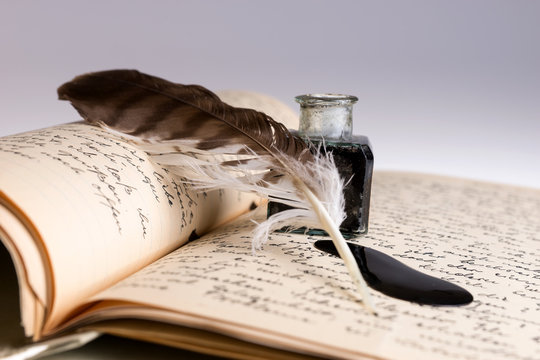 Old writing feather and ink spot with handwritten letter in background