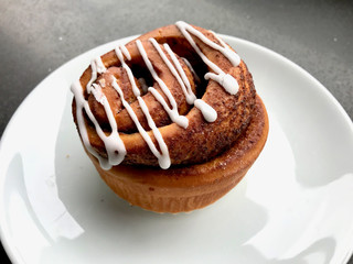 Homemade Fresh Cinnamon Roll / Bun with Cream Sauce served at Cafe Shop with Plate Portion