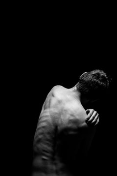 black and white photo of a man from the back light falls from above