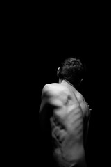 black and white photo of a man from the back light falls from above - obrazy, fototapety, plakaty