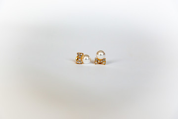 Jewelry gold earrings with gems and pearl on a white background