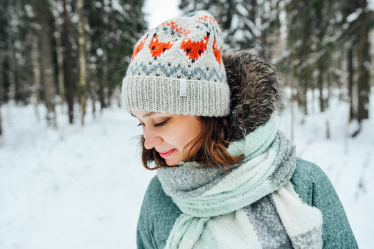 Outdoor close up portrait of young beautiful happy girl, wearing stylish knitted winter hat.