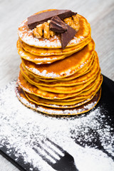 Pancakes served chocolate, walnut and powdered sugar at plate