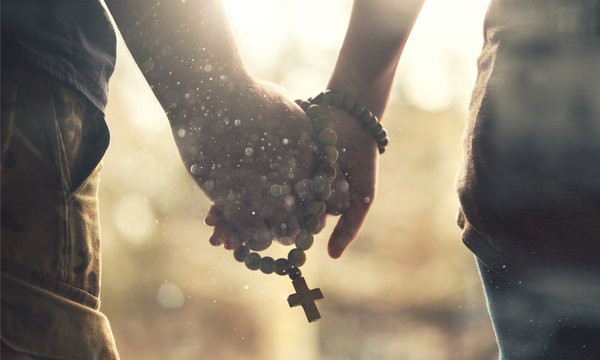 Couple praying together. Holding rosary in hand.