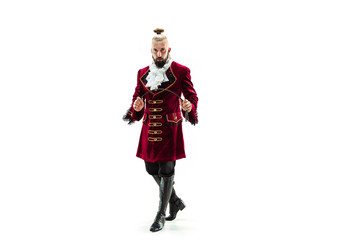 The young man wearing a traditional medieval costume of marquis posing at studio with whip....