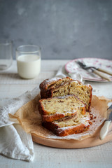Sliced cake on a wooden tray and a glass of milk on a dark background