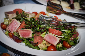 Refreshing salad of fried tuna sliced, grapefruit fillet, avocado, sprouts, tomato, salad in garlic-lemon sauce. Horizontal composition