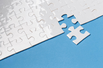 Fototapeta premium Last piece of white puzzle ready to complete the mission on blue background