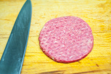 Two homemade beef burgers with mushrooms, micro greens, red onion, fried eggs and beet sauce on wooden cutting board