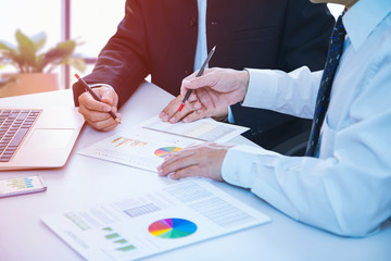 Businessman is deeply reviewing a financial reports for a return on investment or investment risk analysis on a laptop computer notebook.