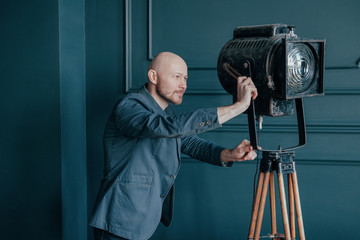 Attractive adult bald man with beard in suit looking at old lighting fixture, video light