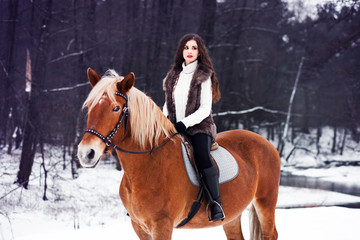 Lady riding a horse, winter walk in the forest near the lake