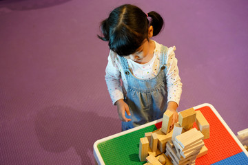 Fototapeta na wymiar Asian kid playing with wooden blocks. Kindergarten educational games.