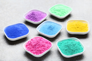 Colorful holi powder in bowls on grey background