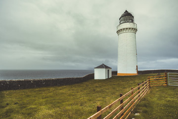 Fototapeta na wymiar Close-up white Campbeltown lighthouse. Northern Ireland. The cloudy rainy sky background. The lonely lighthouse on the Irish shore. Epic ocean view. Stunning autumn landscape.