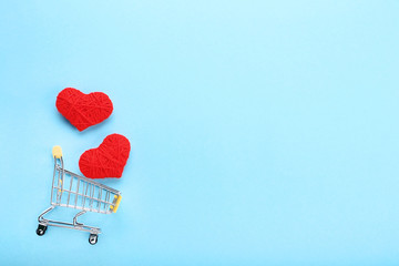 Shopping cart with red rope hearts on blue background