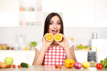 Beautiful woman holding sliced orange fruit and cooking food in the kitchen