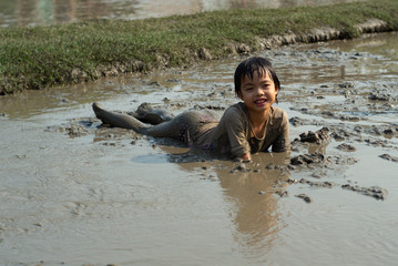 Portrait Asian wet girl enjoys plays in the mud pond and chases group of ducks in the farm.
