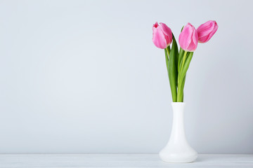 Bouquet of pink tulips in vase on wooden table