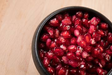 Rote Granatapfel Kerne in schwarzer Porzellan Schale auf Holz Hintergrund