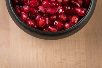 Rote Granatapfel Kerne in schwarzer Porzellan Schale auf Holz Hintergrund