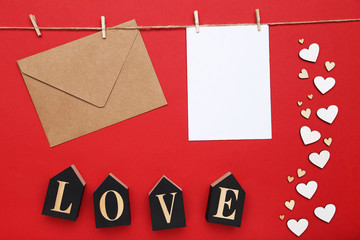 Paper hearts with envelope and word Love on red background