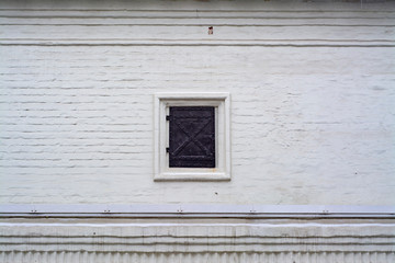 White wall of an old building with shuttered window