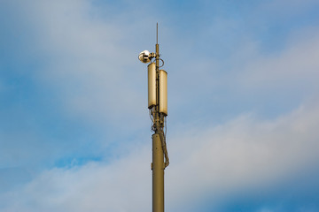 Fototapeta na wymiar A pole with cellular repeaters against a blue cloudy sky