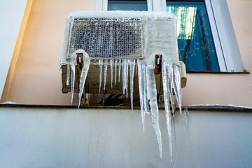 Street block conditioner frozen and covered with icicles and snow in winter