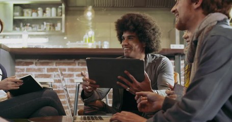 Colleagues and clients talking strategy with laptop and tablet.Group of multiethnic people having informal business team meeting in restaurant lounge.Teamwork,corporate,diversity and social concepts