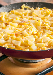 Omelet of potatoes cooking in a pan