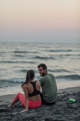 Sportswoman and sportsman Resting on Sandy Beach