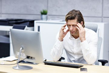 Close up portrait of businessman with headache t workplace