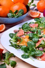 Salad with radicchio, mandarins, red oranges and canned tuna on a white plate