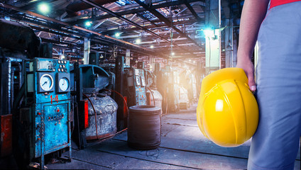 Closeup of worker man with yellow helmet on Industrial zone background, manufacturing facility....