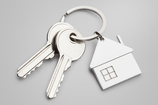 House keys with house shaped keychain on grey background