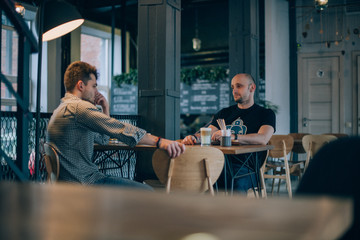 Two young men chatting in a cafe over a cup of coffee