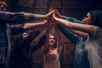 Happy friends join their hands in the air