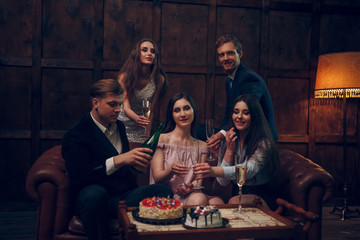 Plakat Cheerful friends celebrate birthday by drinking champagne and eating cake