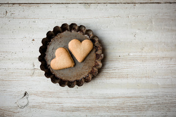 Fototapeta na wymiar Liebe und Backen - Herz Kekse in Backform auf hellem Holz