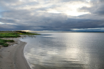 Calm lake at evening under the grey cloudy sky