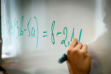 Education in high school, hand with green marker writes maths formula on a whiteboard