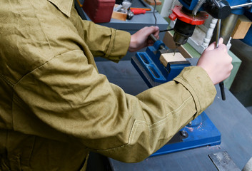 Male student using drilling machine in school workshop, vocational education at school